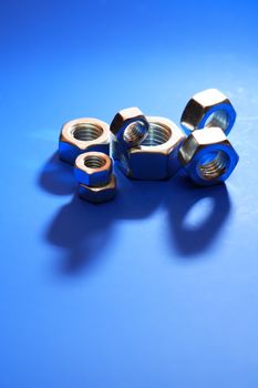 Set of metal nuts on blue background with shadow