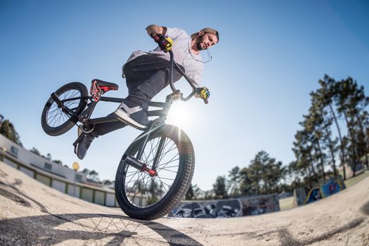 Bmx stunt performed at the top of a mini ramp on a skatepark.