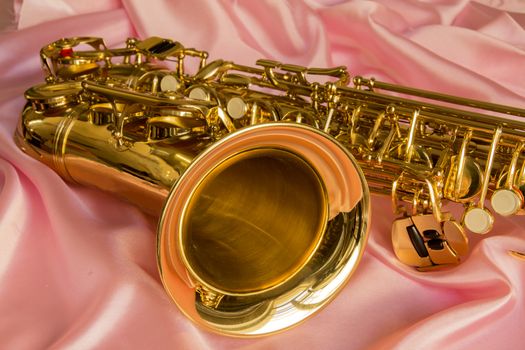 beautiful golden saxophone on delicate Pink silk background