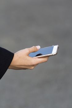 the girl in the arm with a French manicure keeps mobile phone