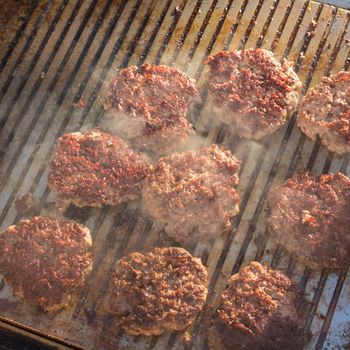 Beef burgers being grilled on food stall grill on international street food festival event. 