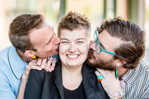 Two gender fluid young men kiss their cute female friend