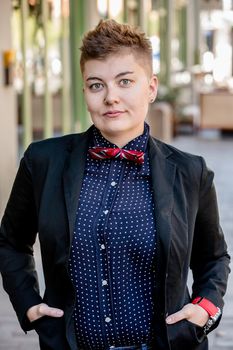 Serious dapper young gender fluid woman on city sidewalk