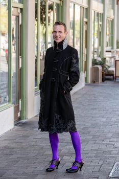 Gender fluid young man in coat and high heels