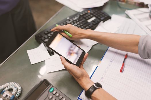 Close up of hand of business man working document and using mobile smart phone in office .