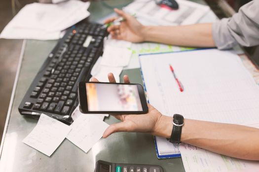 Close up of hand of business man working document and using mobile smart phone in office .