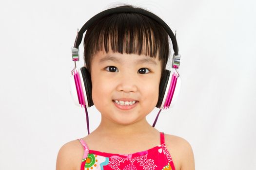 Chinese little girl on headphones smile with plain white isolated background.