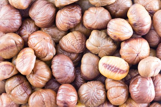 Full frame background texture of fresh whole roasted chestnuts for a healthy seasonal autumn snack or for use in cooking