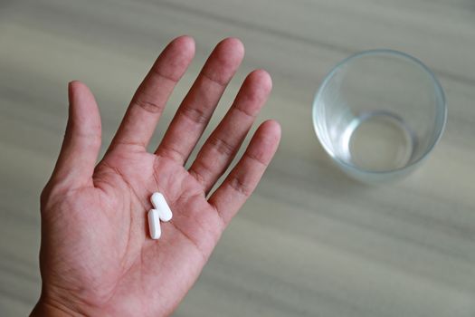 Hands holding pill and glass of water