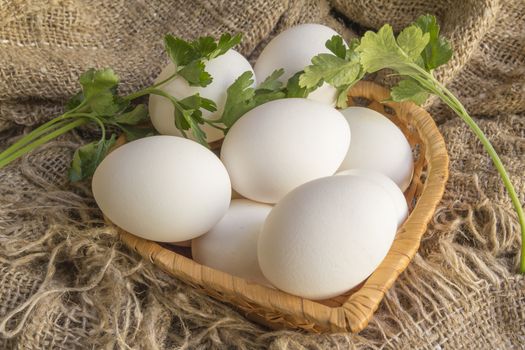 white eggs in a straw plate against the background of the canvas