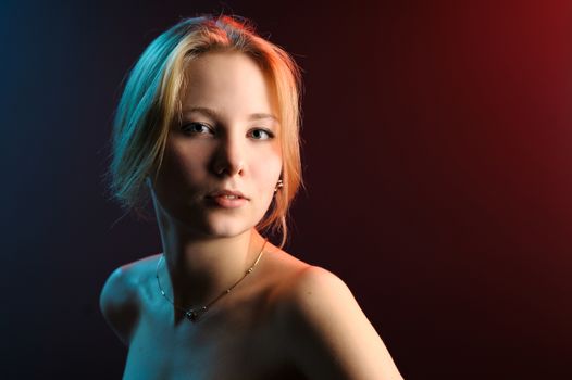 Beautiful girl portrait in blue red light on black background.