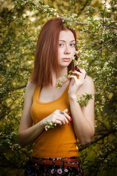 Beautiful redhead girl casually walking under the rays of the sunset in summer forest