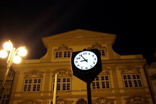 Street Clock at Night Time Against Blurry Building in Prague, Czech Republic