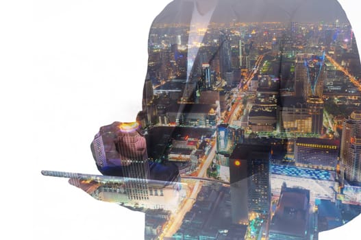 Double exposure of a businessman and a city using a tablet over white background