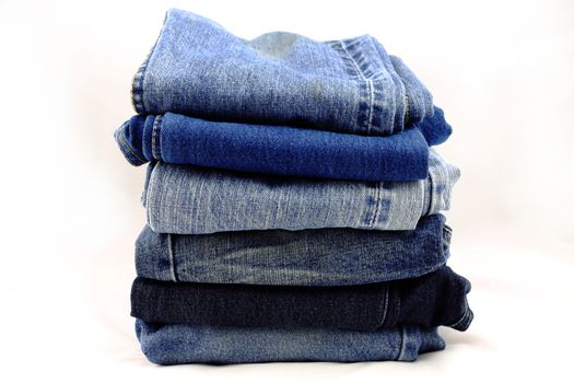 Blue jeans pants pile on a white background.