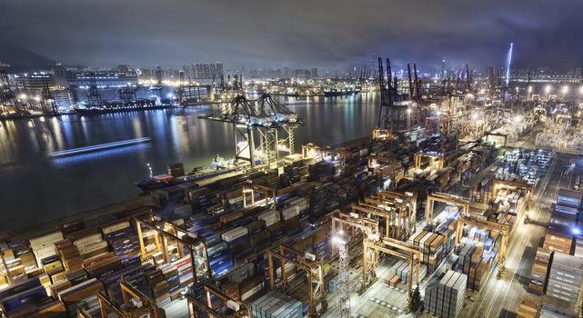 Cargo ship and crane at port reflect on sea bay, hong kong twilight time