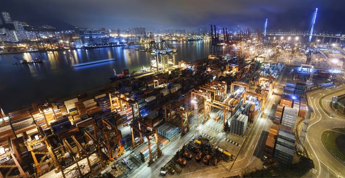 Cargo ship and crane at port reflect on sea bay, hong kong twilight time