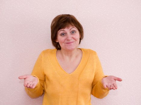 An unsuspecting mature woman shrugs and smiling. Shrug of helplessness