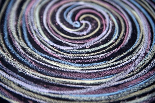 Spirals of different colors drawn with chalk on blackboard
