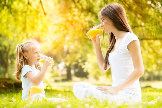 Beautiful Mother and daughter in the nature having little picnic.