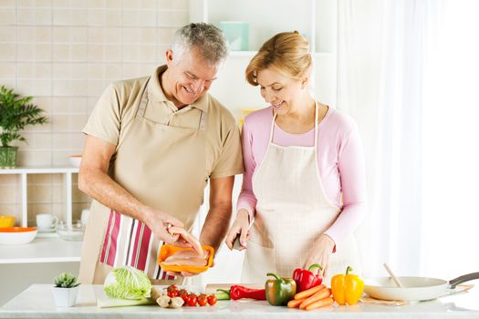 Happy Senior Couple preparing food in the kitchen.