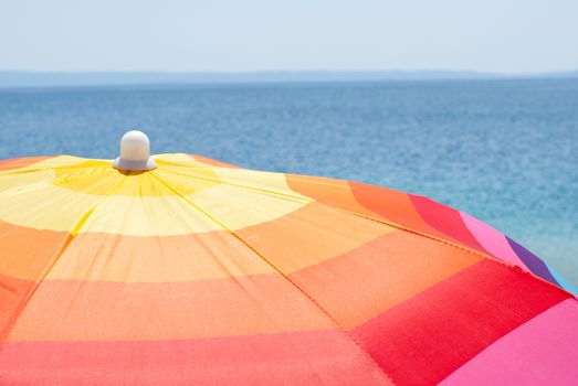 Multicolor beach umbrella on a sunny day and the sea in background