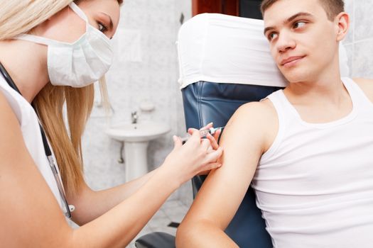 Young man getting flu shot needle vaccination in arm