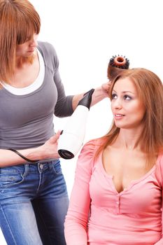 Beautiful young hairdresser drying woman hair