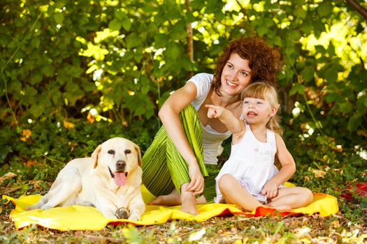 Beautiful mother and daughter relaxing in nature with their dog