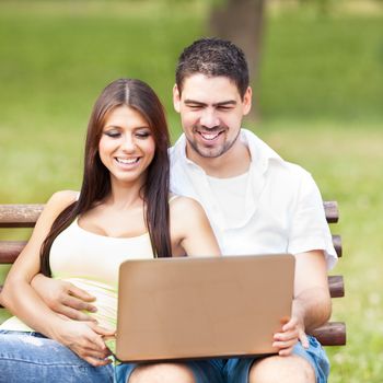 Happy couple using laptop in the nature