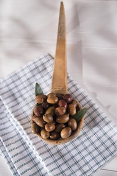 Presentation of a small group of black olives on wooden ladle
