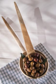 Presentation of a small group of black olives on wooden ladle
