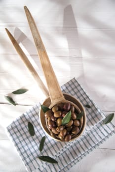 Presentation of a small group of black olives on wooden ladle
