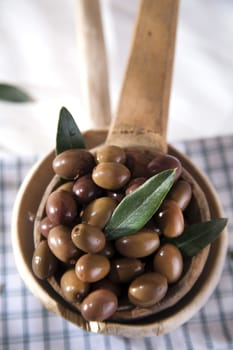 Presentation of a small group of black olives on wooden ladle
