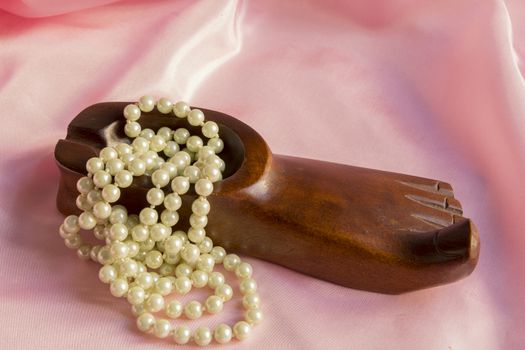 Pearl Necklace in wooden ashtray on a pink silk