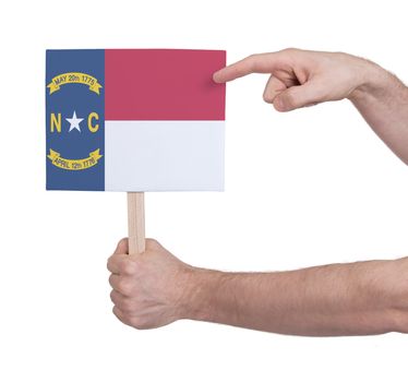 Hand holding small card, isolated on white - Flag of North Carolina