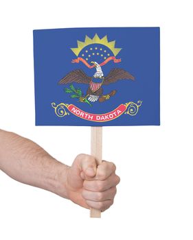 Hand holding small card, isolated on white - Flag of North Dakota