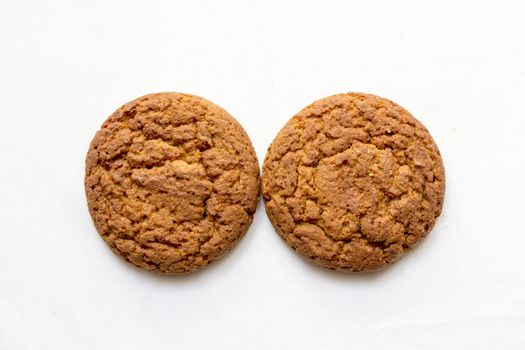 two round oatmeal cookies on a white background