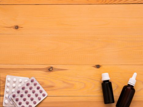 tablets and drops on a light wooden background with copy space. Flat lay or top view