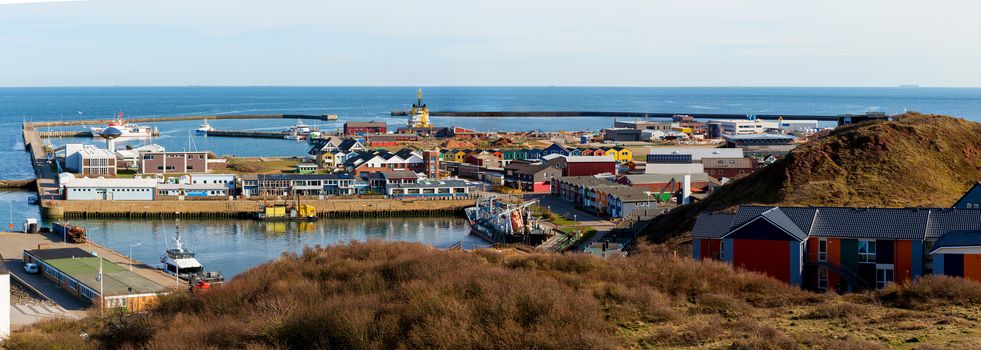 colored Crab fisher hutches at harbor Island Helgoland, Germany, nordic style houses with boat and blue sky, panorama view from hill to north sea