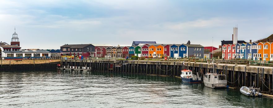 panorama of colored Crab fisher hutches at harbor Island Helgoland, Germany, nordic style houses with boat and blue sky
