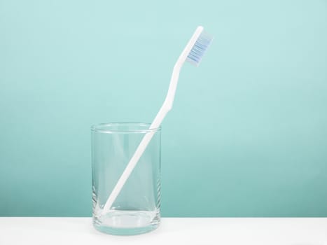 The white toothbrush with small glass for brushing the teeth.