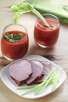 Chunks of pork on the plate and tomato juice with celery in the glass, the morning light, bokeh, defocused background.