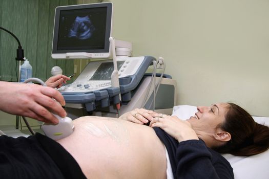 Pregnant woman and doctor hand's with ultrasound equipment during ultrasound medical examination