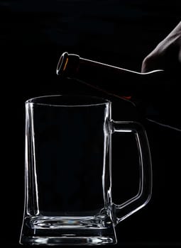 Put beer from bottle on empty glass on black background