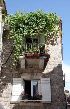 Mediterranean stone medieval house with window shutters and pot plants, Budva, Montenegro