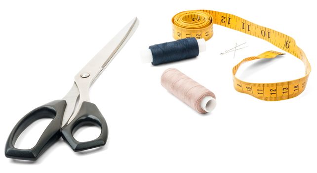 Tailors tools - scissors, spool of thread and tape measure on white