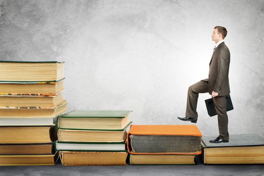 Businessman with portfolio goes up stairs of books. Education concept