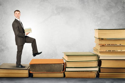 Businessman carries stack of books and walks up stairs of books. Education concept