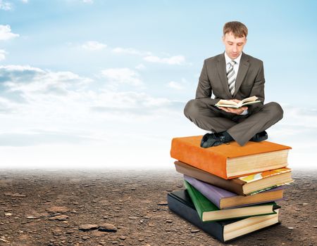 Businessman sitting on stack of books and reading. Education concept